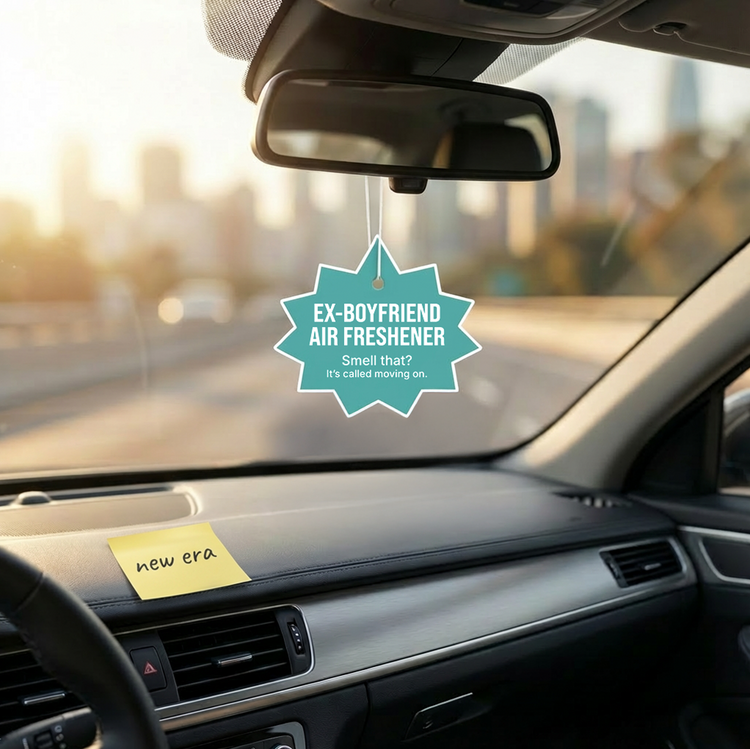 Car interior with an 'Ex-Boyfriend Air Freshener' hanging from the rearview mirror.