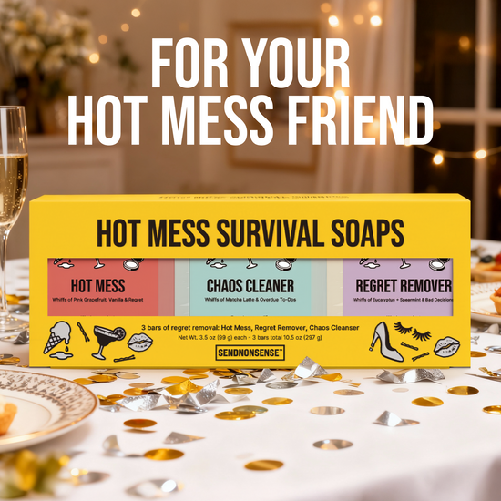 Box of 'Hot Mess Survival Soaps' on a table with confetti and a glass of champagne.