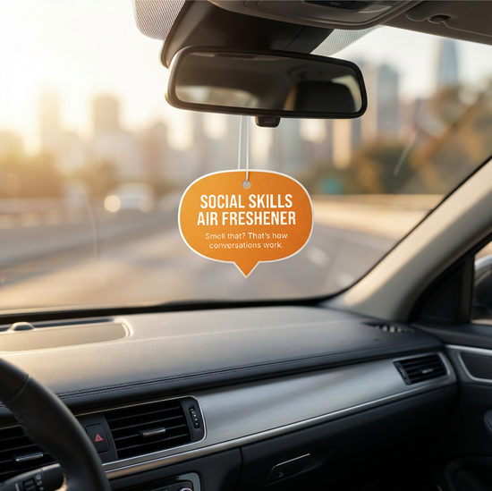 Car interior with a social skills air freshener hanging from the rearview mirror.